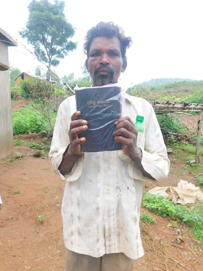 A pastor in India holding his Bible in the Odia language